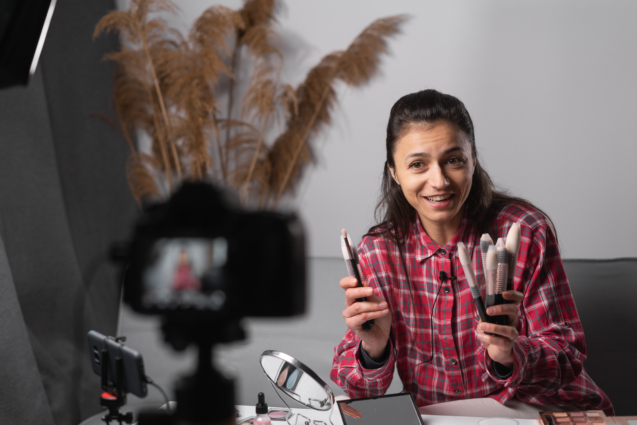 influencer girl livestreaming cosmetics product review in home studio with professional lighting equipment. beauty blogger woman filming daily make up tutorial