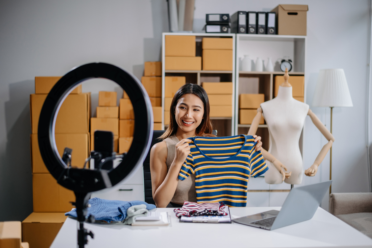 asian woman prepares parcels and checks online orders on tablet and laptop for delivery online shopping and small business success
