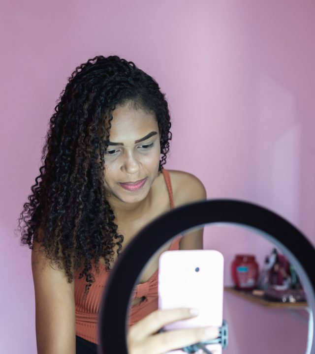 black young woman filming herself dancing at home to share on social media